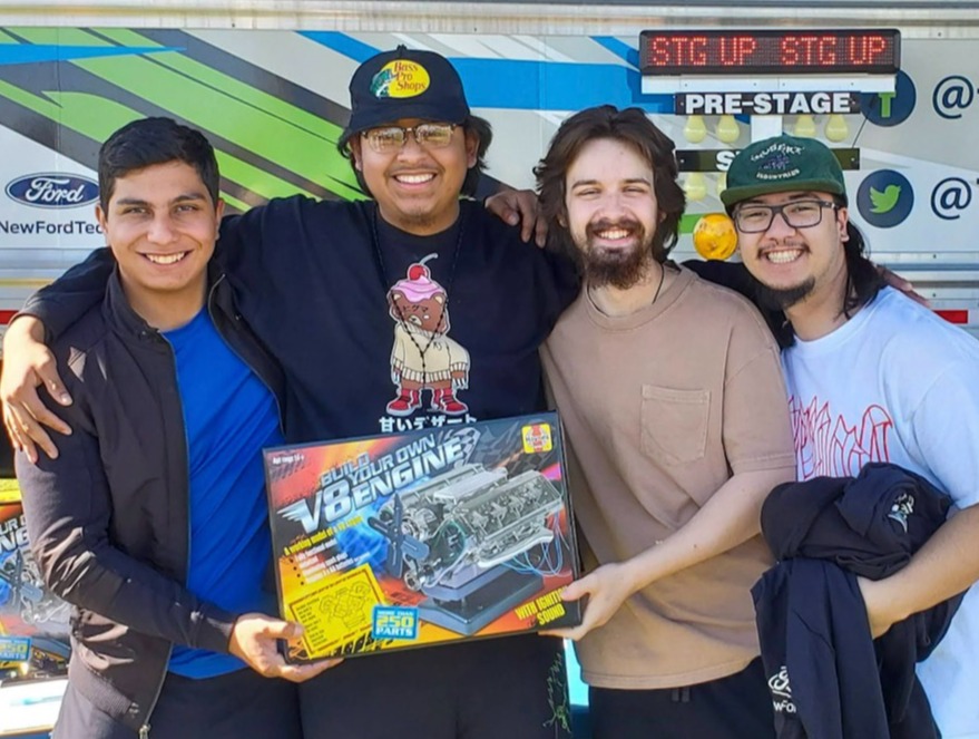 Four young men pose with a model engine kit after winning it at TechForce's Mobile STEM Career Center.